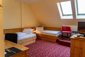 a room with two beds and a red chair at Fichtelberghaus in Kurort Oberwiesenthal