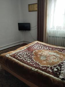 a bed with a blanket on top of it in a room at Guest house SONO adress Derbisheva 202 in Karakol