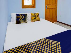 a bed with yellow and blue polka dot pillows on it at OYO 92168 Kost Pak Suyatno Syariah in Ponorogo