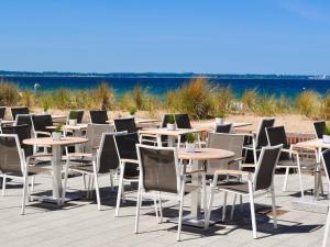 eine Reihe von Tischen und Stühlen am Strand in der Unterkunft Strandhotel Miramar in Timmendorfer Strand