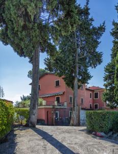 ein rosafarbenes Haus mit Bäumen davor in der Unterkunft Casale Belvedere "L'Ulivo" e "La Terrazza" in Massarosa