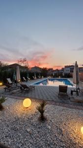 a swimming pool with chairs and umbrellas at sunset at Villa Kotlar in Ohrid