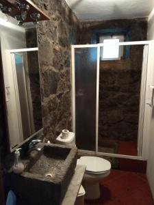 a stone bathroom with a sink and a toilet at Moinho da Cascata in Faja Grande