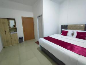 ein Schlafzimmer mit einem großen weißen Bett mit roten Kissen in der Unterkunft Hiast Syariah Residence in Palembang