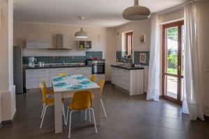 a kitchen with a table and yellow chairs and a kitchen with a table and chairs at Villa Marazia with Garden and Private Parking! in Trecastagni