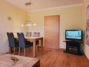 ein Esszimmer mit einem Tisch mit Stühlen und einem TV in der Unterkunft Appartementhaus Residenz Duenengarten in Kühlungsborn