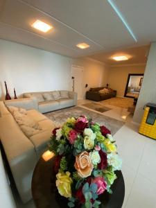 una sala de estar con un gran ramo de flores sobre una mesa en FRENTE MAR - 3 SUITES - 2 VAGAS, en Itapema