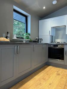 a kitchen with white cabinets and a window at Quirky, Luxury Hideaway in Llanbrynmair