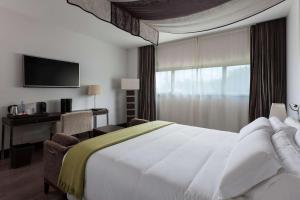 a hotel room with a white bed and a window at NH Collection Santiago de Compostela in Santiago de Compostela