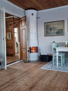 een woonkamer met een open haard en een houten vloer bij Ronehamn Bed and Breakfast in Hemse