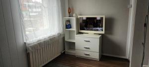 - une télévision sur une commode dans une chambre avec fenêtre dans l'établissement ApartmentMR, à Maribor