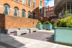 a courtyard with benches in front of a brick building at Brand New Luxury 1-Bed Apartment in Liverpool in Liverpool