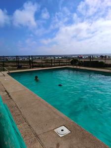 a person swimming in a swimming pool near the ocean at Dpto Bordemar 1 in Las Cruces