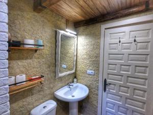 een badkamer met een wastafel, een spiegel en een deur bij Cazorla Paraíso Resort in Cazorla