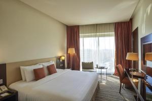 a hotel room with a large bed and a large window at Safir Hotel Doha in Doha
