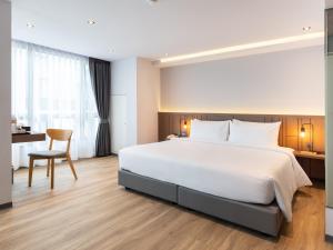 a bedroom with a large white bed and a desk at Pure Eleven Hotel Bangkok in Makkasan