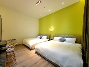 two beds in a room with a green wall at 翠綠色民宿 in Feng-li