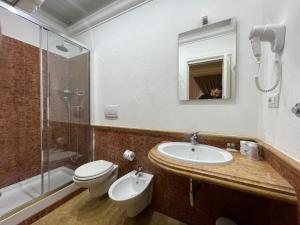 bagno con lavandino, servizi igienici e specchio di Ambasada Suite a Roma