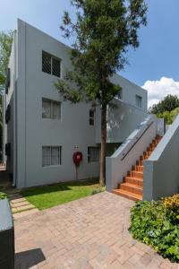 een wit gebouw met een boom ervoor bij Radstays - 43 Madison Palms in Johannesburg
