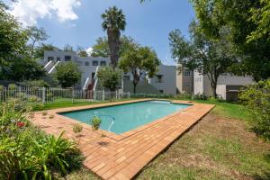 een zwembad in een tuin met een houten terras bij Radstays - 43 Madison Palms in Johannesburg