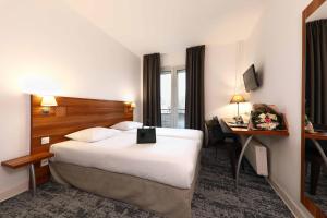 een hotelkamer met een groot bed en een bureau bij The Originals City, Hôtel Colmar Gare in Colmar