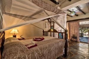 a bedroom with a bed with a canopy at Jacaranda Beach Resort in Watamu