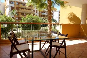 een glazen tafel en stoelen op een balkon met een gebouw bij Parque Recoleta 2 PISCINAS - CERCA DE PLAYA in Punta Prima