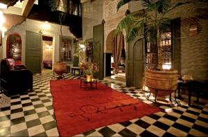 uma sala de estar com um tapete vermelho num piso xadrez em BKAN RIAD MARRAKECH em Marrakech