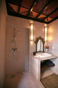 uma casa de banho com um chuveiro, um lavatório e um espelho. em BKAN RIAD MARRAKECH em Marrakech