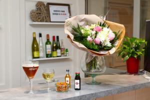 un jarrón de flores en un mostrador con copas de vino en The Originals City, Hôtel Colmar Gare, en Colmar
