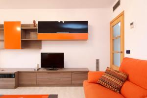 ein Wohnzimmer mit einem orangenen Sofa und einem Flachbild-TV in der Unterkunft AT259 Costa Coral in Torredembarra