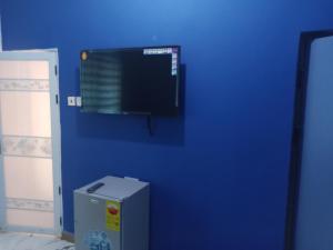 pared azul con TV en una habitación en Dexxy's Palace Hotel, en Koforidua