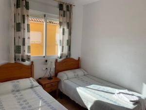 Duas camas num pequeno quarto com uma janela em Kione Anamar em Alcossebre