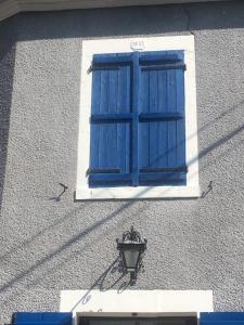 een blauw raam aan de zijkant van een gebouw met een lamp bij VERONIQUE 58 ANNAY in Annay