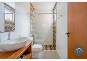 a bathroom with a white sink and a toilet at Casa em Garopaba - Piscina - Forno para pizza - Ar condicionado - 3 quartos in Garopaba