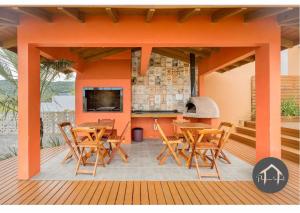 a patio with wooden tables and chairs and a fireplace at Casa em Garopaba - Piscina - Forno para pizza - Ar condicionado - 3 quartos in Garopaba +43 photos
