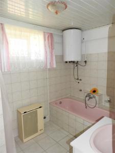 ein Badezimmer mit einer rosa Badewanne und einem Waschbecken in der Unterkunft Ela`s Ferienoase Haus Ketsching in Görcsönydoboka
