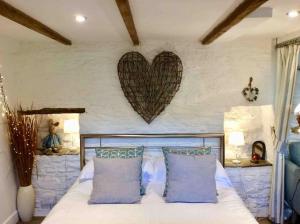 a bedroom with a bed with a heart on the wall at Unique Thatched Retreat near Salcombe and Beaches in South Milton