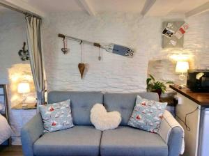 a living room with a blue couch with a heart pillow at Unique Thatched Retreat near Salcombe and Beaches in South Milton