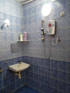 y baño de azulejos azules con lavabo y ducha. en QQ Homestay en Ipoh