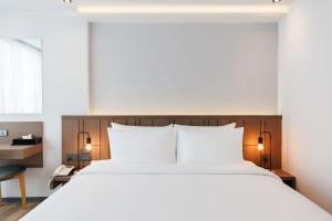 Pure Eleven Hotel Bangkok في Makkasan: غرفة نوم مع سرير أبيض كبير ومكتب