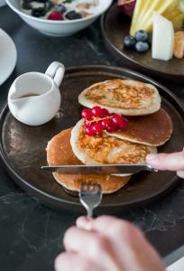 a person is eating pancakes on a plate with a spoon at Elitis House - Suite & Spa in Nova Milanese +92 photos