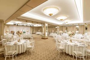 un salón de banquetes con mesas blancas, sillas y flores en Ramada by Wyndham Istanbul Golden Horn en Estambul