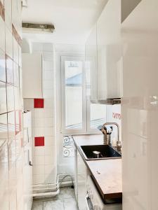 une cuisine blanche avec un évier et une fenêtre dans l'établissement Cosy T2 in Neuilly sur Seine metro 1, à Neuilly-sur-Seine