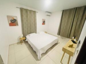 Dormitorio blanco con cama y mesa en VILLA FRUIT A PAIN T3, en Cayenne