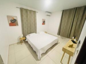 a white bedroom with a bed and a table at VILLA FRUIT A PAIN T3 in Cayenne