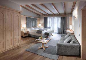 a hotel room with a bed and a couch at Gardena Grödnerhof - Hotel & Spa in Ortisei