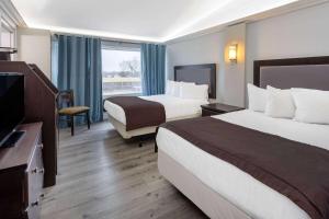 um quarto de hotel com duas camas e uma televisão de ecrã plano em Travelodge by Wyndham Sarnia em Sarnia