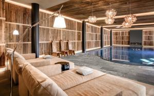 a pool room with two beds and a swimming pool at Gardena Grödnerhof - Hotel & Spa in Ortisei