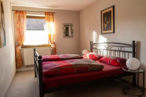 um quarto com uma cama com lençóis vermelhos e uma janela em Ferienwohnung Meier Eveline em Dollnstein